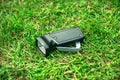 Black retro flashlight with manual drive, lying on the green grass.