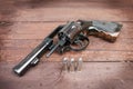 Black revolver gun with bullets isolated on wooden background