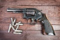 Black revolver gun with bullets isolated on wooden background Royalty Free Stock Photo