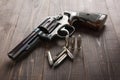 Black revolver gun with bullets isolated on wooden background