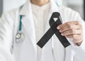 Black ribbon awareness in doctor`s hand for Melanoma and skin cancer, Narcolepsy, Primary Biliary Cirrhosis Cholangitis Royalty Free Stock Photo