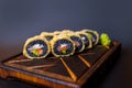 Black rice hot tempura roll with salmon, tuna, avocado, haddock and cream cheese served on wooden board isolated on background Royalty Free Stock Photo