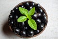 Black ripe Syzygium cumini fruits. Dark black java plum in a wood bowl at isolated white background. Green mint leaf on top of Royalty Free Stock Photo