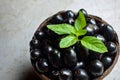 Black ripe Syzygium cumini fruits. Dark black java plum in a wood bowl at isolated white background. Green mint leaf on top of Royalty Free Stock Photo