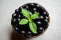 Black ripe Syzygium cumini fruits. Dark black java plum in a wood bowl at isolated white background. Green mint leaf on top of Royalty Free Stock Photo