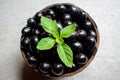 Black ripe Syzygium cumini fruits. Dark black java plum in a wood bowl at isolated white background. Green mint leaf on top of Royalty Free Stock Photo