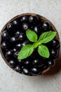 Black ripe Syzygium cumini fruits. Dark black java plum in a wood bowl at isolated white background. Green mint leaf on top of Royalty Free Stock Photo