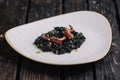 Black risotto with cuttlefish ink and octopus tentacles on irregular shape plate Royalty Free Stock Photo