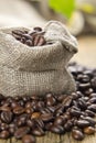 Black roasted coffee beans in a small burlap sack