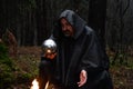 A black-robed monk sits by a fire in the forest and looks into a divination ball. Mysticism and magic, sorcerers and witches 3 Royalty Free Stock Photo