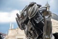 Black robot transformer with glowing red eyes against the background of urban old buildings;