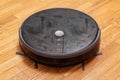 Black robot vacuum cleaner on the parquet