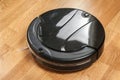 black robotic vacuum cleaner runs on the laminate floor Closeup. The robot is controlled by voice commands for direct cleaning. Mo