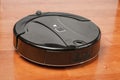 Black robotic vacuum cleaner runs on laminate floor closeup. robot controlled by voice commands for direct cleaning. modern