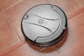 black robotic vacuum cleaner runs on the laminate and on the tile floor Closeup. The robot is controlled by voice commands for dir