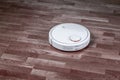 Black robotic vacuum cleaner runs on laminate and on tile floor. Robot controlled by voice commands for direct cleaning. Modern
