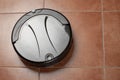 black robotic vacuum cleaner runs on the tile floor Closeup. The robot is controlled by voice commands for direct cleaning. Modern