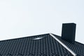 Black roof of a new house. Roof covering with steel tiles. Black roof with a skylight and a chimney Royalty Free Stock Photo