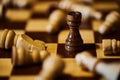 Black rook stands upright on chessboard, surrounded by fallen white pieces