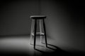 In a black room, a solitary white stool stands like a beacon of contrast, creating an intriguing visual composition