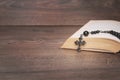 Black rosary on the Bible at wooden table