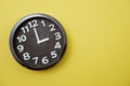 Black round clock showing three o`clock on yellow background Royalty Free Stock Photo