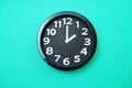 Black round clock showing two o`clock on green background Royalty Free Stock Photo