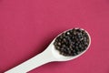Black round dried peas in a wooden spoon on a red background Royalty Free Stock Photo