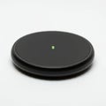 Black round wireless charging pad on a white background. It features a smooth, flat Royalty Free Stock Photo