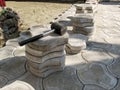 Black rubber mallet lies on top of a pile of gray figured paving slabs among unfinished work on the paving tiles in patio. Concept