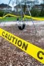 Black rubber swings in closed public playground surrounded by yellow caution tape during Corvid-19 Coronavirus pandemic Royalty Free Stock Photo