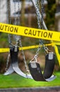 Black rubber swings in closed public playground surrounded by yellow caution tape during Corvid-19 Coronavirus pandemic Royalty Free Stock Photo