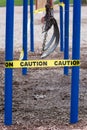 Black rubber swings in closed public playground surrounded by yellow caution tape during Corvid-19 Coronavirus pandemic Royalty Free Stock Photo