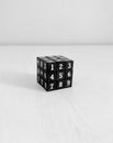 Black Rubik Cube with numbers on white wooden table shot of the part of side with numbers 1,2,4,5