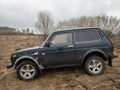 Black Russian off-road car Lada Niva 4x4 VAZ 2121 / 21214 parked on the field.