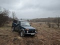 Black Russian off-road car Lada Niva 4x4 VAZ 2121 / 21214 parked on the field.