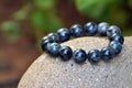 Black rutilated quartz bracelet on the statue in the garden with copy space on the left side. Royalty Free Stock Photo