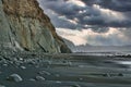 Black sand beach and limestone cliffs under a dramatic sky