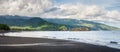 Black sand beach near by the town Ende. The landscape is remarkable with the mountains, Clouds and light in background, Ende, East