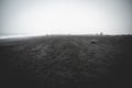 Black Sand Beach Reynisfjara, Iceland during foggy weather, people walking in the distance Royalty Free Stock Photo