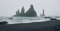 The black sand beach of Reynisfjara with waves hitting the shore on foggy rainy stormy day Vik, Iceland