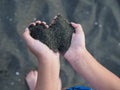 Black sand in children`s hands in the form of a heart Royalty Free Stock Photo