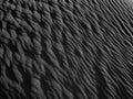 Black Sand dune. Black Sand beach macro photography. Background, texture, wave pattern of oceanic sand on the beach, black. Textur Royalty Free Stock Photo