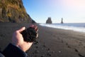 Black sand in hand Vik Reynisfjara beach Reynisdrangar Iceland Atlantic ocean