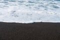 Black sand volcanic beach and sea wave