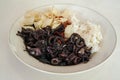 Black sauce stir fried squid with rice and crackers on top of a plate, isolated by white background Royalty Free Stock Photo