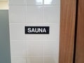 Black sauna sign on white tiled wall with sauna room to the right Royalty Free Stock Photo