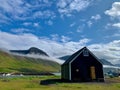 Black Scandinavian cottage in Iceland's Westfjords with green hills in the background