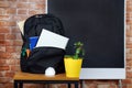 Black school backpack with notebooks and pens on the background of the board and flower Royalty Free Stock Photo