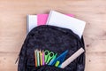 Black school bag with a set of stationery for the student and with white notebook in it. Back to school concept Royalty Free Stock Photo